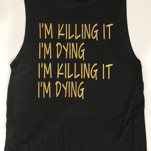 Puede incluir: Camiseta negra sin mangas con letras doradas que dicen "I'm killing it I'm dying I'm killing it I'm dying".