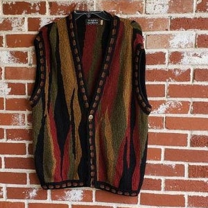 Puede incluir: Un chaleco multicolor con botones y cuello en V. El chaleco presenta rayas verticales en tonos negro, marr&oacute;n, rojo y verde. Los bordes est&aacute;n ribeteados con un borde marr&oacute;n oscuro. El chaleco est&aacute; colgado de una percha negra.