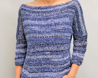 May include: A long-sleeved, boat-neck sweater crafted from variegated blue yarn. The garment features a horizontal crochet pattern with alternating solid and open-work stitch rows, creating a textured, multi-tonal appearance in shades of navy and light blue.