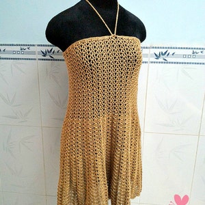 May include: A brown crochet halter dress with a loose fit and a scalloped hem.