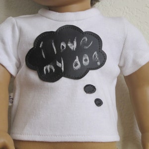 May include: White t-shirt with a black felt cloud applique that says "I love my dog" in white chalk.