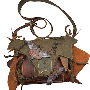 Puede incluir: Bolso de hombro de cuero hecho a mano en tonos marrón, verde oliva y beige. El bolso presenta aplicaciones decorativas de mariposas y costuras intrincadas. La correa ajustable es de color marrón oscuro.