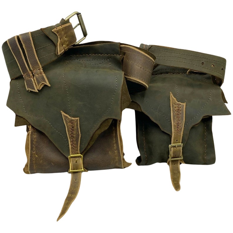 Op de afbeelding: Twee bruine leren buidels met een bruine leren riem. De buidels hebben een klep met een gespsluiting en een lange riem. De riem heeft een gespsluiting.