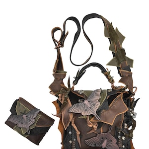 Könnte beinhalten: Ein handgefertigtes Lederhandtaschen- und Geldbörsen-Set. Die Tasche zeichnet sich durch ein einzigartiges Design mit geschichtetem braunem, schwarzen und grünen Leder aus, verziert mit Metallmotten-Verzierungen und dekorativen Perlen. Das Set beinhaltet einen Schulterriemen und eine kleine Geldbörse.