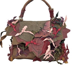 Könnte beinhalten: Handgefertigte Lederhandtasche in Braun-, Grün- und Burgundertönen, verziert mit blattförmigen Applikationen und einem Schmetterlingsdesign. Mit einem oberen Griff und dekorativen Akzenten.
