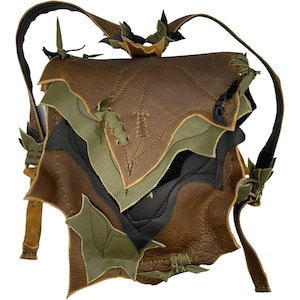 May include: A brown leather backpack with green and black leaf-shaped details. The backpack has a unique, layered design and is secured with a buckle.