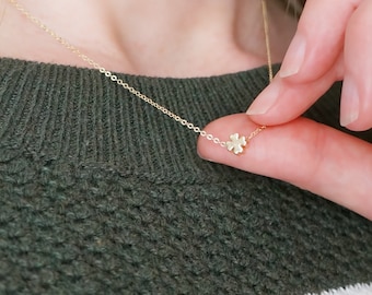 May include: A delicate gold necklace with a small four-leaf clover pendant.