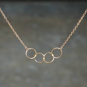 May include: A gold chain necklace with five interlocking circles hanging from it.