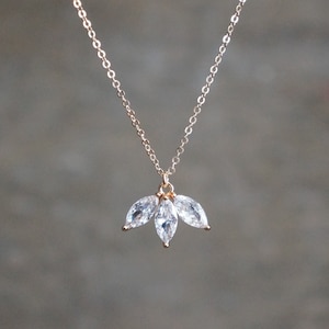 May include: A delicate gold chain necklace with a pendant featuring three clear marquise-shaped crystals.