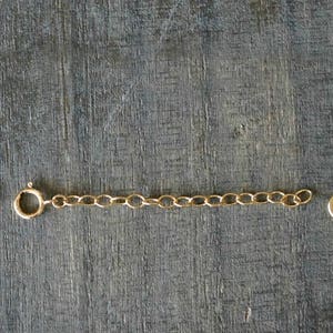 May include: A gold chain necklace with a lobster clasp closure. The chain is made of small, oval-shaped links.