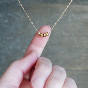May include: A delicate gold necklace with a row of small, faceted gold beads.