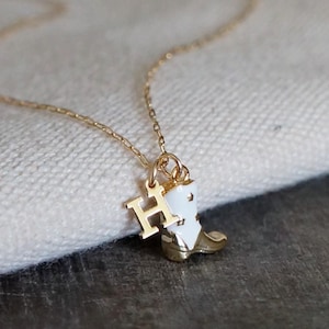 May include: Gold chain necklace with a white enamel boot charm and a gold letter H charm.