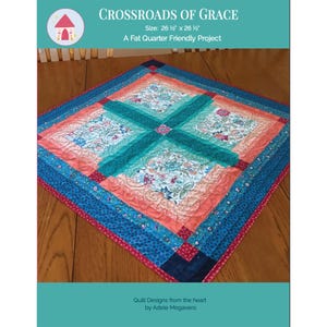 Może przedstawiać: Kwadratowa kołdra z kwiatowym wzorem i krzyżem. Kołdra ma wymiary 67,3 cm na 67,3 cm i zawiera odcienie niebieskiego, koralowego i turkusowego. Widoczny jest tekst "CROSSROADS OF GRACE" i "A Fat Quarter Friendly Project".