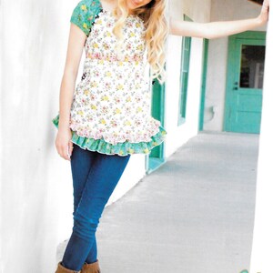 May include: A young person wearing a white peasant top with a floral print and green trim. The top has a ruffled hem and is paired with blue jeans and brown suede boots with fringe. The text "Flower Child" is written in a whimsical font with a flower graphic. The text also says "a peasant top for tweens and teens #27".