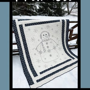 May include: A white quilt with a black and white snowman design. The quilt is framed with black and white fabric and has a snowflake pattern. The quilt is on a snowy background. "Framed" is written in black at the top of the image. "Tricia Lynn Maloney Orphan Quilt Designs for Villa Rosa Designs" is written at the bottom of the image.