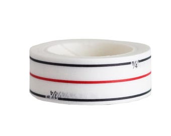 May include: A white, circular baking tape roll with black and red lines. The tape has measurements of 1/4 inch printed on it. This tape is designed for precise baking and cooking.