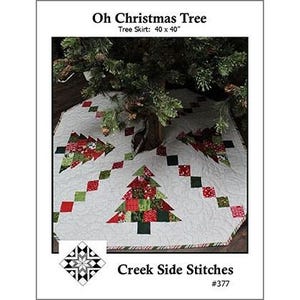 May include: A white quilted Christmas tree skirt measuring 40 by 40 inches, featuring a patchwork design of red and green Christmas trees and diagonal square patterns. The text reads Oh Christmas Tree, Tree Skirt: 40 x 40, and Creek Side Stitches #377.