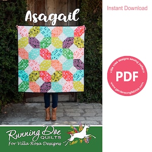 May include: A colourful quilt pattern called "Asagail" by Running Doe Quilts for Villa Rosa Designs. The quilt is made up of a variety of geometric shapes in bright colours, including pink, red, orange, yellow, green, blue, and purple. The quilt is being held up by a person in front of a brick wall. The image also includes a pink circle with the text "PDF" and "www.gardensongfabrics.com".