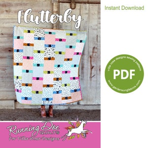 May include: A colorful quilt pattern called "Flutterby" by Villa Rosa Designs. The quilt is made up of squares of different colors and patterns, including pink, blue, green, and brown. The quilt is hanging on a wooden wall. The text "Instant Download" and "PDF" are visible in the image. The image also includes the text "Running Doe Quilts for Villa Rosa Designs".