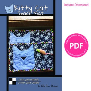 Könnte beinhalten: Ein gesteppter Snack-Matte mit zwei blauen Katzenköpfen und einem Spielzeug-Maus auf einem schwarzen Hintergrund mit weißen Spinnennetz-Designs. Die Matte hat einen bunten Rand und den Text "Kitty Cat Snack Mat". Enthält ein PDF-Schnittmuster.