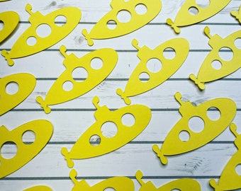 May include: A collection of yellow paper cutouts of submarines. Each submarine has three portholes and a propeller.