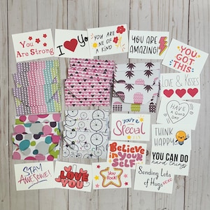May include: A collection of colorful greeting cards and patterned envelopes. The cards feature positive messages like "You Are Strong," "Love You," and "You Are Amazing!" The envelopes display various designs, including polka dots and bicycles.