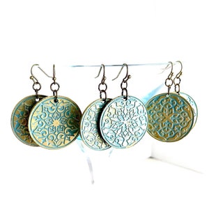 Może przedstawiać: Trzy pary złotych i turkusowych kolczyków z ozdobnym wzorem mandali.