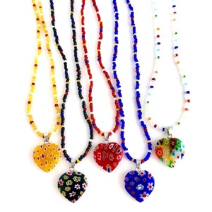 May include: Five necklaces with heart-shaped pendants. Each necklace has a different colored beaded chain and a different patterned heart pendant. The pendants are made of glass and have a colorful floral design.