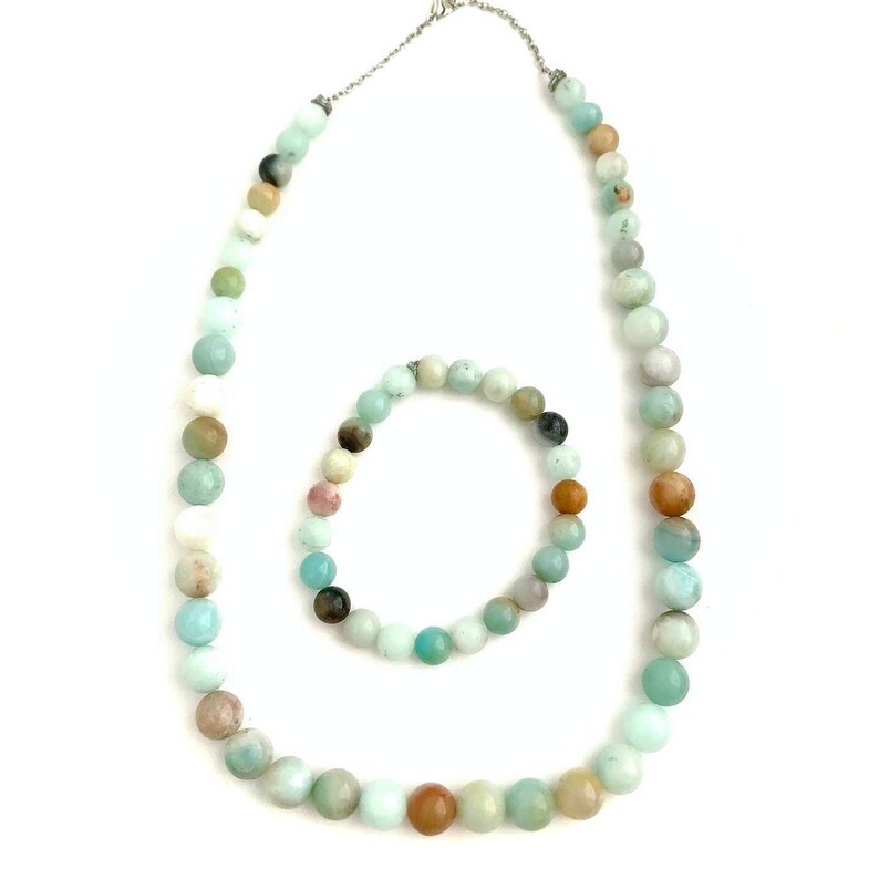 May include: A set of green and brown gemstone beads, including a necklace and a bracelet. The necklace is longer and has a silver clasp. The bracelet is shorter and has no clasp.