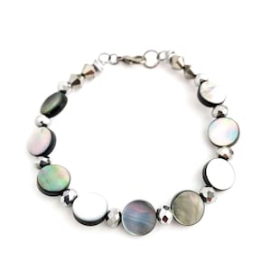 May include: A silver bracelet with black and white shell beads and silver metal beads.