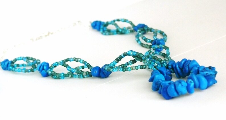 May include: A multi-strand necklace made of blue and green glass beads with a large blue turquoise pendant.