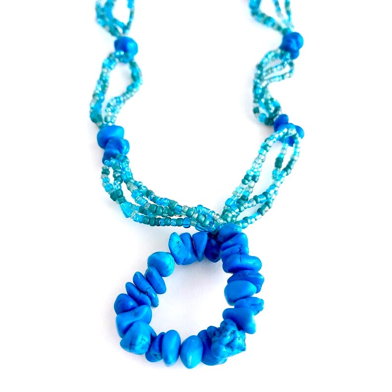 May include: A blue beaded necklace with a circle pendant made of larger blue beads.