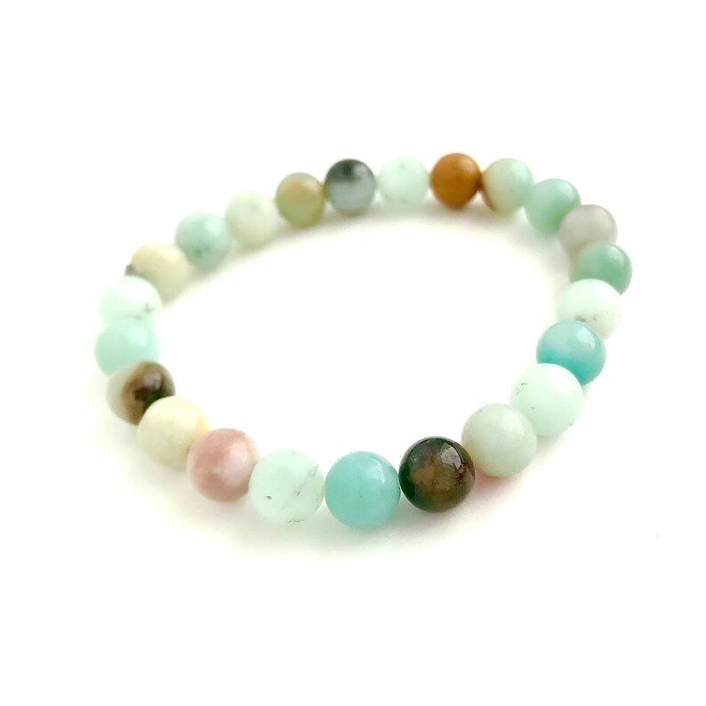 May include: A bracelet made of various colored gemstone beads, including green, brown, pink, and white.