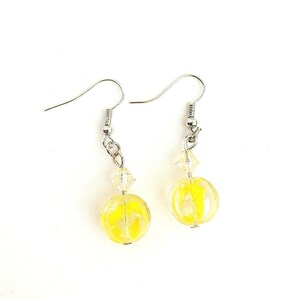 May include: A pair of yellow glass bead earrings with silver hooks and crystal accents.