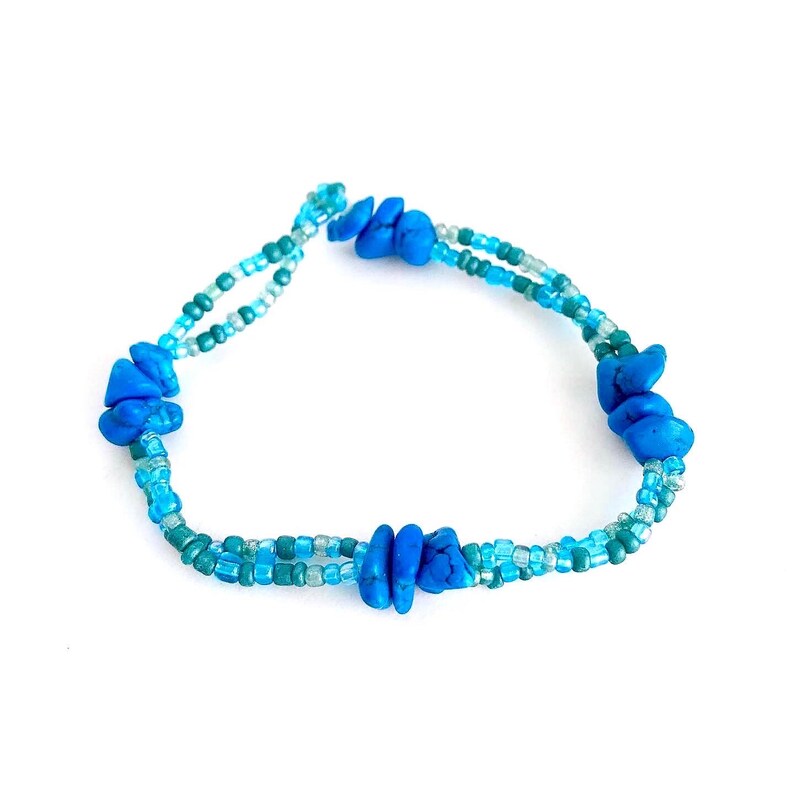 May include: A blue beaded bracelet with turquoise-colored stones. The bracelet is made of two strands of beads, one light blue and one dark blue.
