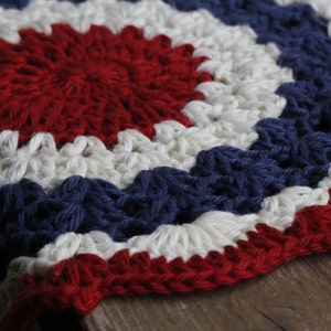 May include: A crocheted round rug with red, white, and blue yarn in a circular pattern.