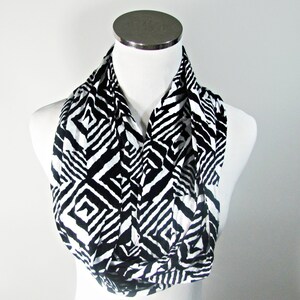 May include: A black and white geometric patterned infinity scarf. The scarf is made of a soft, stretchy fabric and is perfect for adding a touch of style to any outfit.