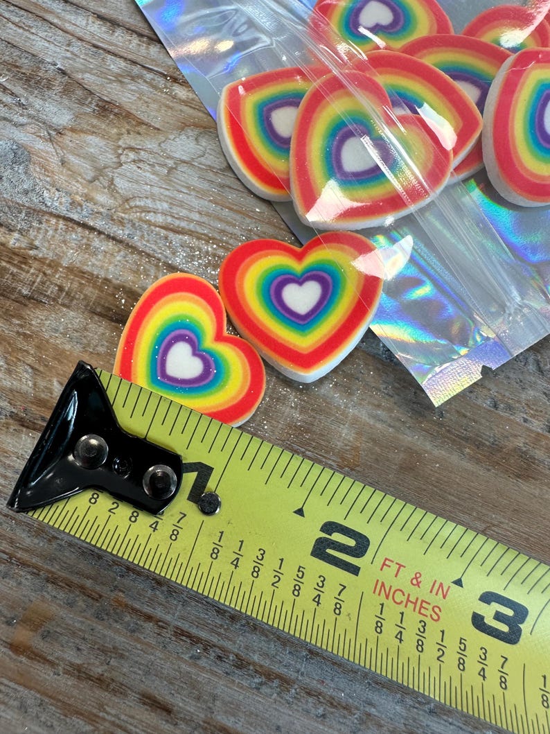 May include: A close-up of a measuring tape next to a bag of rainbow heart-shaped decorations. The tape measures 1 7/8 inches.