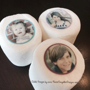 以下が含まれることがあります： 3つの白いマシュマロに、食べられる画像が印刷されています。画像は子供たちです。最初のマシュマロは、ストライプのシャツを着た赤ちゃんの画像の周りに青い縁取りがあります。2番目のマシュマロは、ストライプのドレスを着た長い髪の若い女の子の画像の周りに紫色の縁取りがあります。3番目のマシュマロは、短い茶色の髪の若い男の子の画像の周りに赤い縁取りがあります。マシュマロの下には、「Edible Images by www.NeverForgottenDesigns.com」というテキストが印刷されています。