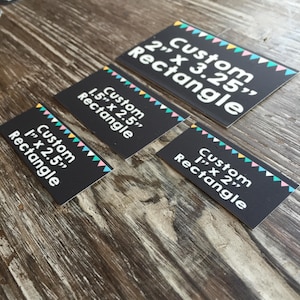 May include: Four black rectangular cards with white text and colorful bunting trim. The cards are labeled "Custom Rectangle" with varying dimensions: 2" x 3.25", 1.5" x 2.5", 1" x 2.5", and 1" x 2".