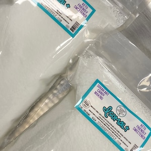 Op de afbeelding: Twee zakken witte Isomalt-suiker, een keto-vriendelijke zoetstof, voor het maken van snoep. Elke zak is ge&euml;tiketteerd met "Sugar Art Supply" en bevat 2 pond (906 gram) Isomalt. De zakken zijn verzegeld en klaar voor gebruik.