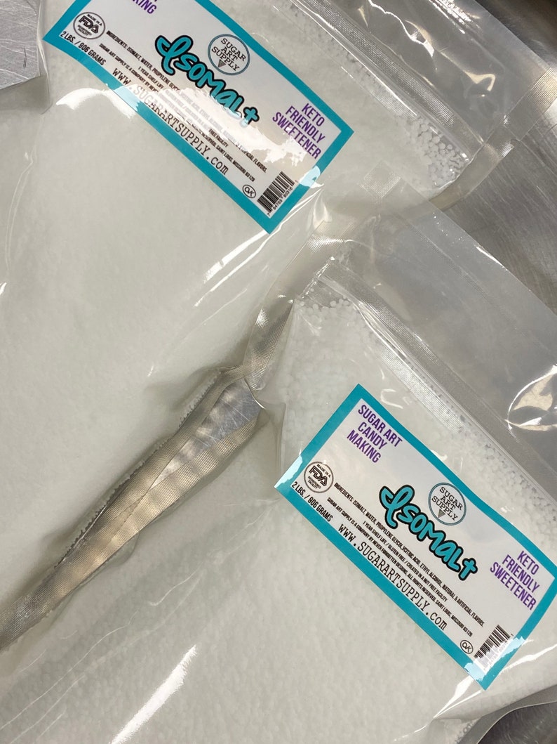Op de afbeelding: Twee zakken witte Isomalt-suiker, een keto-vriendelijke zoetstof, voor het maken van snoep. Elke zak is ge&euml;tiketteerd met "Sugar Art Supply" en bevat 2 pond (906 gram) Isomalt. De zakken zijn verzegeld en klaar voor gebruik.