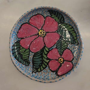 A unique 6-inch handcrafted earthenware plate featuring a flower design.