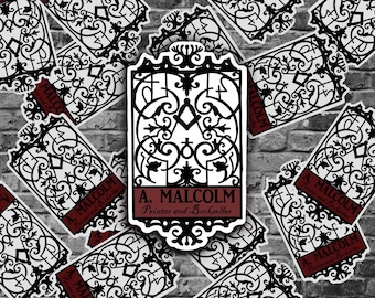 May include: A black and white sticker with an ornate design of a gate. The sticker has the text "A. Malcolm Printer and Bookseller" in a red banner.