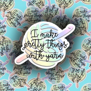 May include: A sticker with a rainbow yarn ball and a crochet hook. The text on the sticker reads "I make pretty things with yarn."