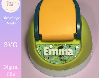 Puede incluir: Un archivo SVG listo para Glowforge, de color verde y naranja, para una etiqueta de nombre personalizada con el nombre "Emma" en letras blancas sobre un fondo de purpurina verde y rosa.