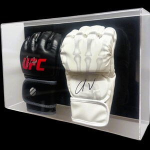May include: A pair of black and white boxing gloves in a clear display case. The black glove has the UFC logo on it and the white glove is signed "DV".