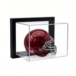 May include: A glossy dark red football helmet with a silver face mask and a small American flag decal on the side, enclosed within a clear acrylic display case featuring a solid black rectangular frame border for wall mounting or shelf display.