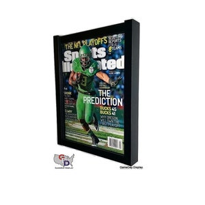 May include: A black framed magazine display case with a Sports Illustrated magazine featuring a football player in a green uniform. The magazine cover reads "The Prediction: Ducks 45 Bucks 41".