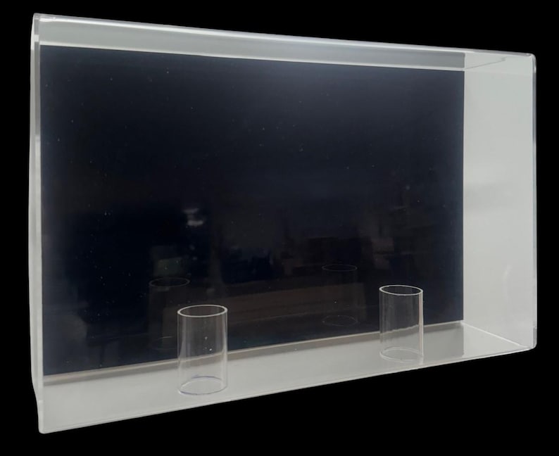 May include: A clear acrylic display case with two clear acrylic cylinders inside. The case has a black background.